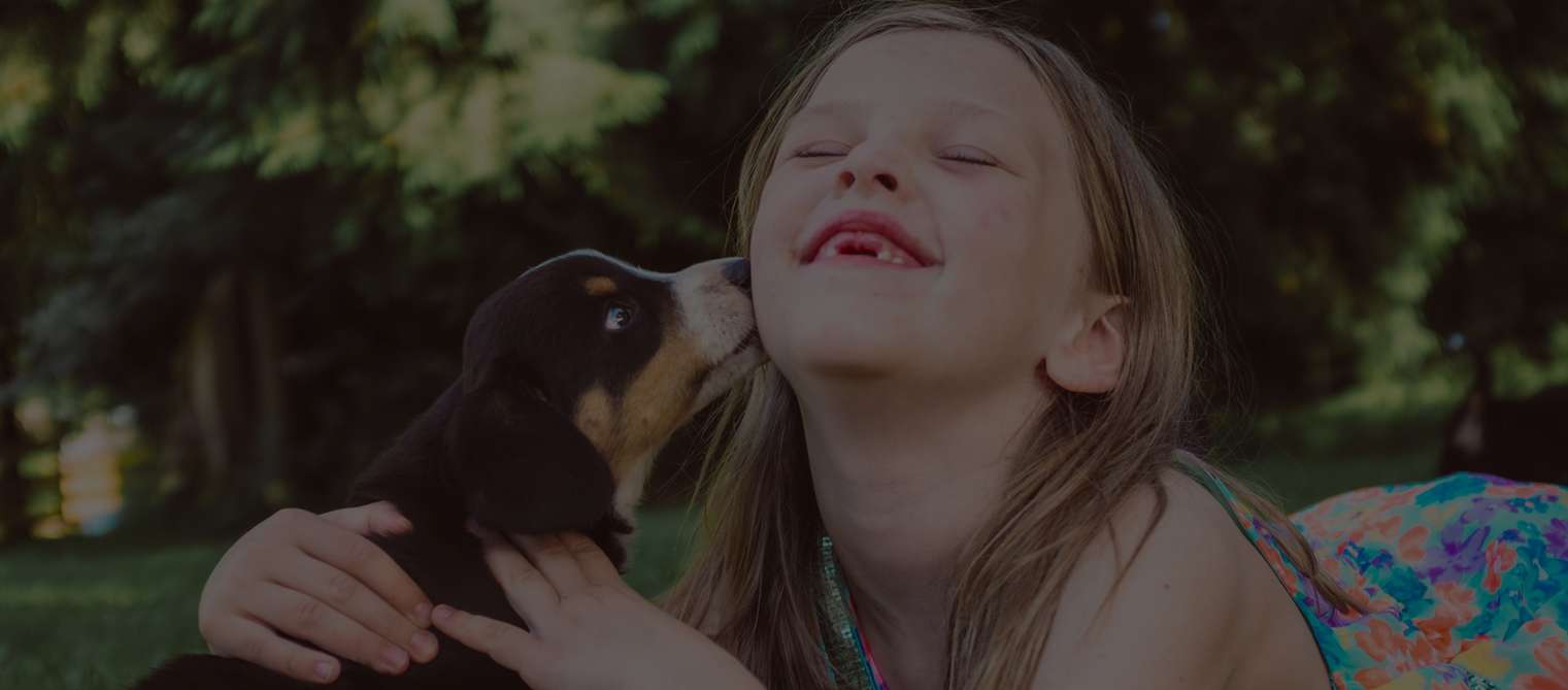 Young girl with Entlebucher Mountain Dog outdoors.